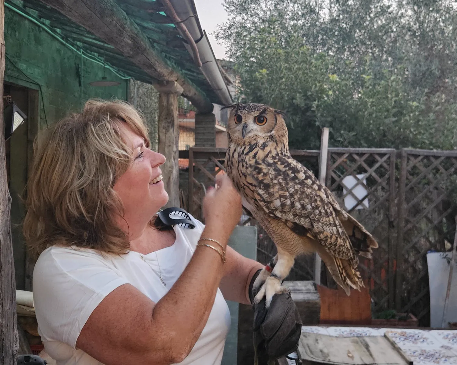 Angelique lacht naar een oehoe die op haar handschoen zit