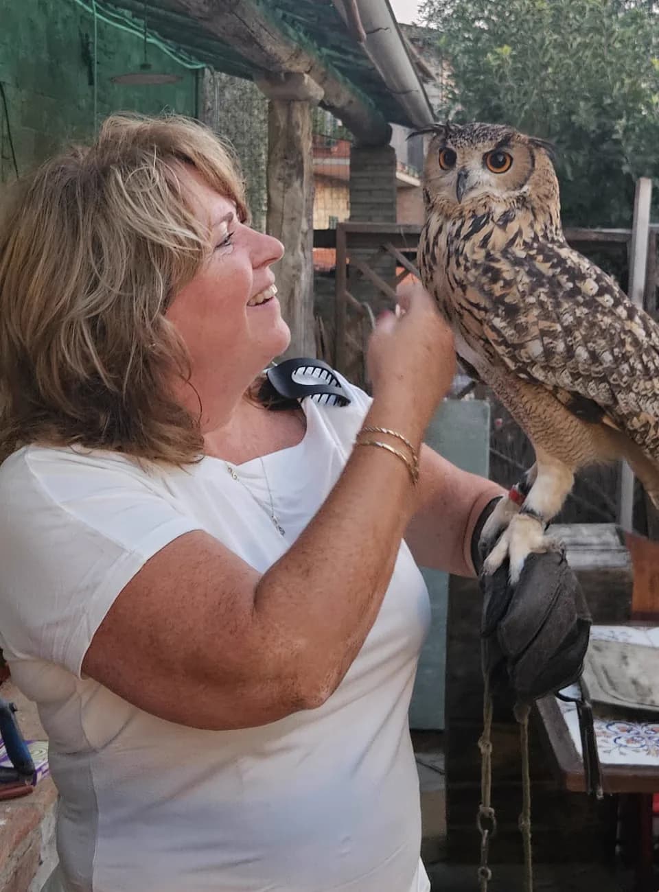 Angelique lacht naar een oehoe die op haar handschoen zit